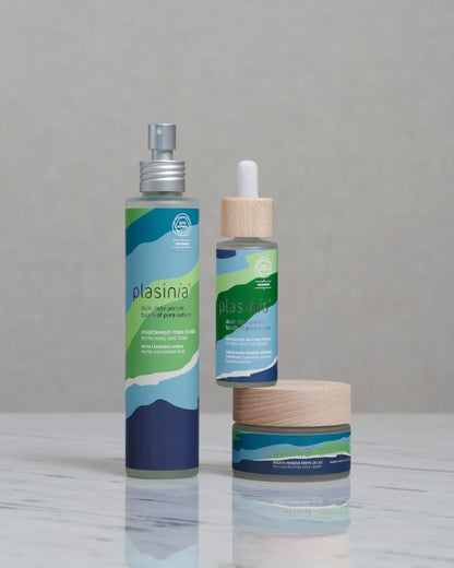 Plasinia skincare products including a spray bottle, dropper, and jar on a gray background