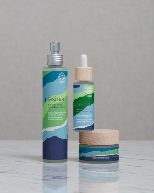 Plasinia skincare products including a spray bottle, dropper, and jar on a gray background