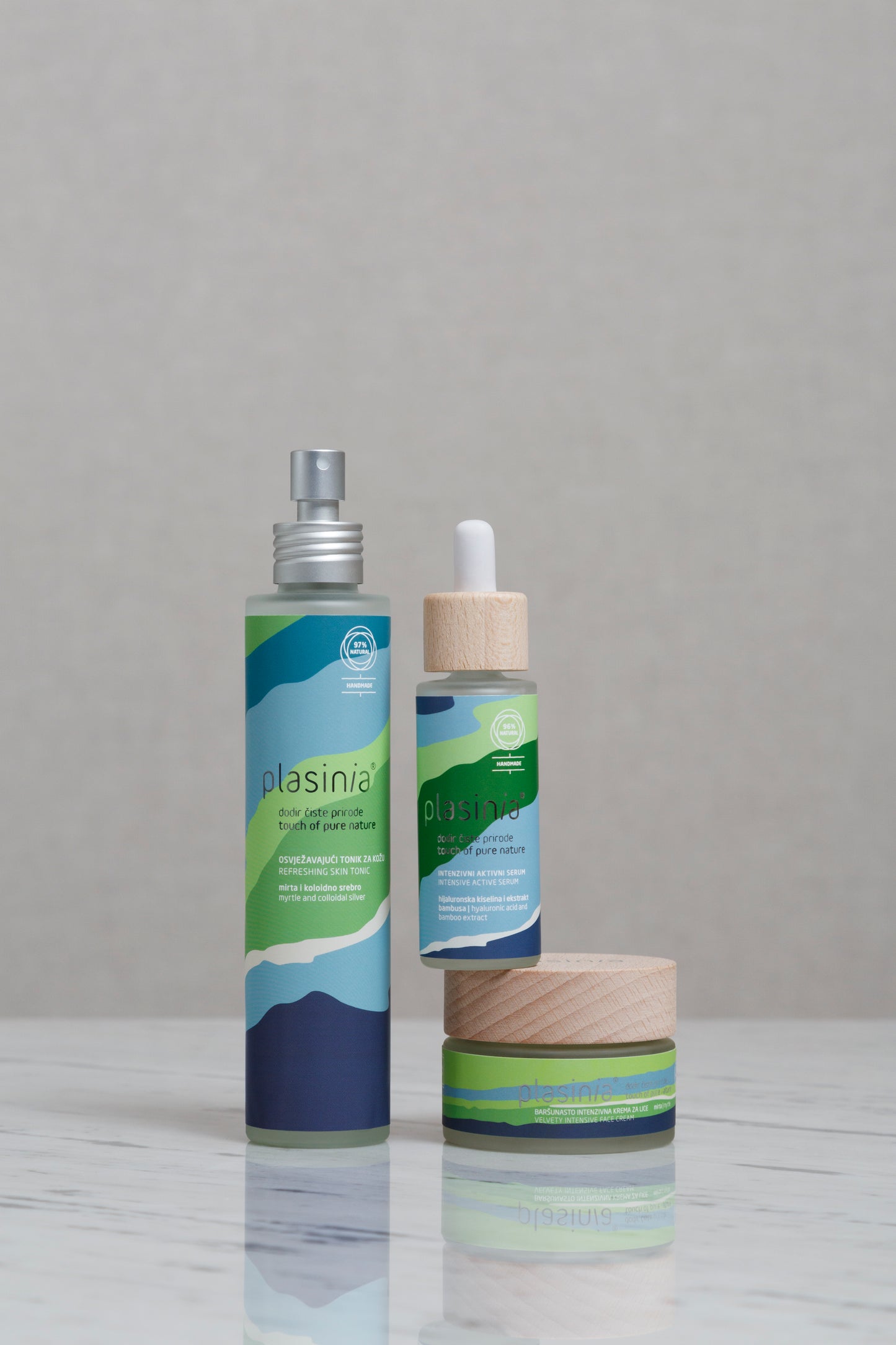 Three skincare products with green and blue packaging on a gray background