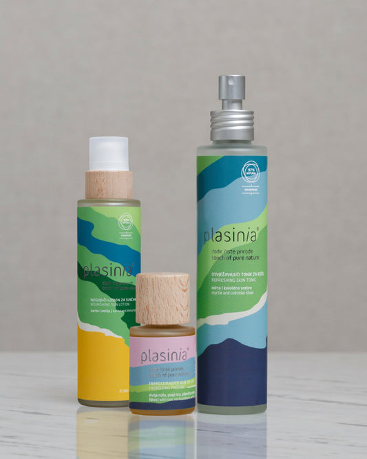 Three Plasinia bottles on a reflective surface with a neutral background